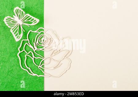 Schmetterlings- und Rosenblüten aus Schnitzpapier oder Schnitt auf grünem und gelbem Hintergrund mit leerem Platz für Ihren Text oder Ihre Nachricht. Stockfoto