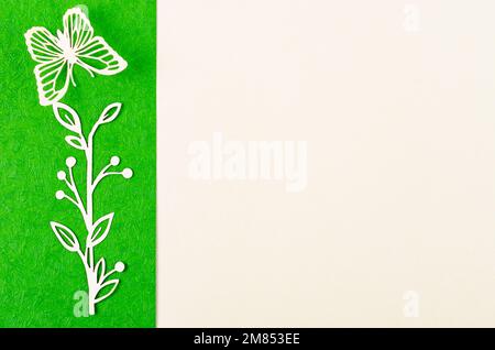 Schmetterling und Blume aus geschnitztem Papier oder Schnitt auf grünem und gelbem Hintergrund mit leerem Platz für Ihren Text oder Ihre Nachricht. Stockfoto