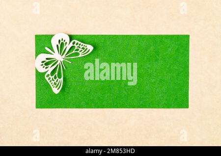Ein Schmetterling aus geschnitztem Papier oder Schnitt auf grünem und gelbem Hintergrund mit leerem Platz für Ihren Text oder Ihre Nachricht. Stockfoto