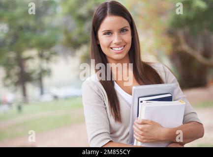 Sie ist Eine A-Klasse-Schülerin. Eine wunderschöne junge Schülerin, die draußen steht und ihre Bücher hält. Stockfoto
