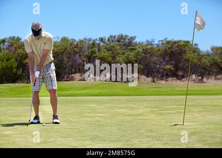 Das ist für das Spiel. Aufnahme über die gesamte Länge eines reifen Golfers, der ein Grün auflegt. Stockfoto