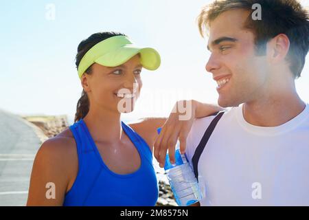 Sie haben ein gemeinsames Interesse an Fitness. Ein junges, sportliches Paar, das draußen steht. Stockfoto