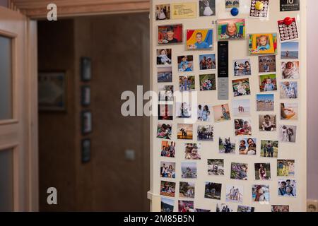 Ternopil, Ukraine - 11. Januar 2023: Kühlschranktür gefüllt mit vielen Erinnerungsfotos der Familie. Stockfoto