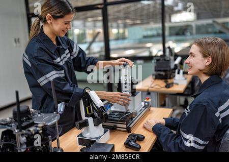 Ingenieurin sitzt im Roboterfabrikationsraum und prüft die Qualität der elektronischen Steuerplatine Stockfoto