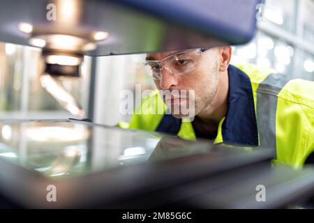 Ingenieur sitzt im Roboterfabrikationsraum und verwendet das Messmikroskop Maschinenprüfung Mikrochip Stockfoto