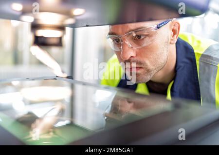 Ingenieur sitzt im Roboterfabrikationsraum und verwendet das Messmikroskop Maschinenprüfung Mikrochip Stockfoto