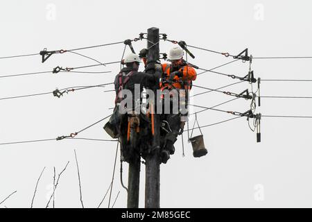 Bridport, Dorset, Großbritannien. 12. Januar 2023 Wetter in Großbritannien. WESTERN Power-Arbeiter, die an einem nassen und windigen Tag einen neuen Telegrafenmast in Bridport in Dorset installieren, werden von dem starken Regen durchnässt. Bildnachweis: Graham Hunt/Alamy Live News Stockfoto