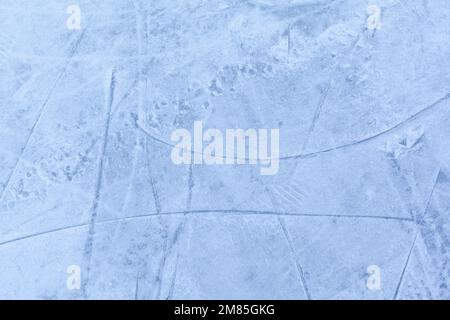 Leere Eisbahn mit Schlittschuhspuren nach der Sitzung im Freien. Eislaufbahn Textur mit Schnee bei Tageslicht bedeckt. Nahaufnahme von blauem Eislaufboden, CO Stockfoto