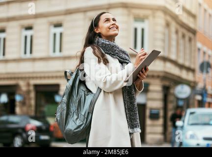 Kreative Frau, Tablet und Schreiben in der Stadt mit Vision, Idee oder Inspiration für Design mit Lächeln für Reisen. Glückliche Frau, die den Touchscreen hält Stockfoto