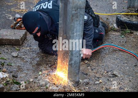 Garzweiler, Deutschland. 11. Januar 2023. Ein Polizist entfernt einen Stahlbalken mit einem Schneidbrenner, die Polizei begann mit der Räumung des Dorfes Luetzerath am 11. Januar 2023, das Dorf Luetzerath an der Westseite des Garzweiler-Braunkohlebergwerks wird im Januar 2023 ausgegraben, Luetzerath, 11. Januar 2023, Kredit: dpa/Alamy Live News Stockfoto