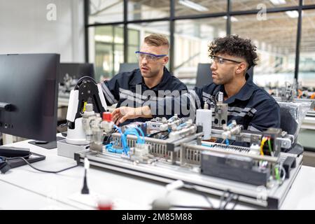 Ingenieur sitzt im Roboterfabrikationsraum und prüft die Qualität der elektronischen Schalttafeln Stockfoto