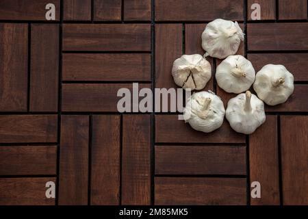 Holzdielen mit Knoblauchhintergrund. Background-Use-Essen, Lebensmittelzutat, Kochkonzept. Ansicht von oben, flach liegend, Kopierbereich. Stockfoto