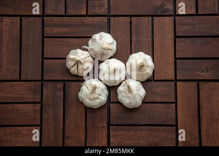 Holzdielen mit Knoblauchhintergrund. Background-Use-Essen, Lebensmittelzutat, Kochkonzept. Ansicht von oben, flach liegend, Kopierbereich. Stockfoto