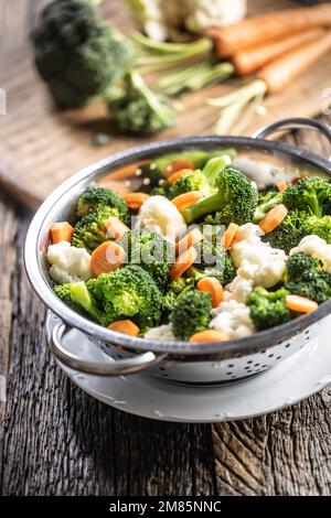 Gedämpfter Brokkoli, Karotten und Blumenkohl in einem Dampfgarer aus Edelstahl. Gesundes Gemüsekonzept. Stockfoto