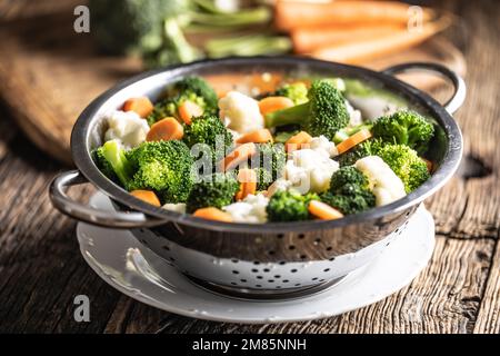 Gedämpfter Brokkoli, Karotten und Blumenkohl in einem Dampfgarer aus Edelstahl. Gesundes Gemüsekonzept. Stockfoto