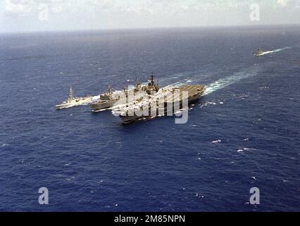 Eine Hafenbogenansicht des Nachfüllölers USS ROANOKE (AOR-7), der während der Übung RIMPAC '86 eine laufende Nachfüllung mit dem Flugzeugträger USS RANGER (CV-61) und der kanadischen Fregatte HMCS TERRA NOVA (F-259) durchführt. Die australische Fregatte HMAS DARWIN (04) ist im Hintergrund. Betreff Betrieb/Serie: RIM PAC '86 Land: Pazifik (POC) Stockfoto