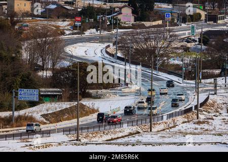 Sekigahara, Japan - 25. Dezember 2022: Leichter Verkehr auf einer kurvenreichen Straße durch eine Kleinstadt im Schnee Stockfoto