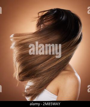 Beauty, Haar und Salon mit einer Modellfrau im Studio auf braunem Hintergrund für die Keratin-Haarpflege. Gesundheit, Luxus und Haarpflege mit einem Jungen Stockfoto