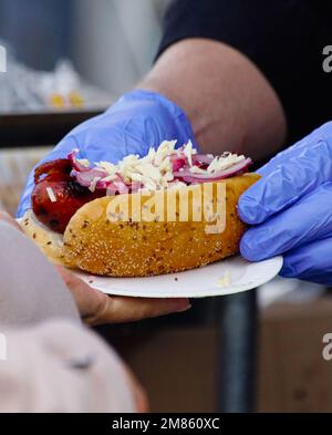 Cropped Hand serviert Würstchen mit Brot im Freien Stockfoto