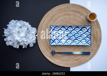 Japanischer oder chinesischer Tisch mit traditioneller Tischdecke und Essgeschirr mit Hintergrund und weißem Hintergrund. Speise- und Restaurantkonzept. Flach verlegt. Stockfoto