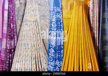 Künstlerische Vielfalt Schattierungen Farben Ornamente Muster, Nahaufnahme von gestapelten Saris oder Sarees im Display des Einzelhandels. Stockfoto