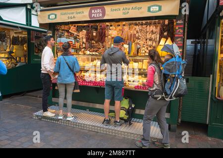 Bozen Markt, Blick auf Menschen, die Speisen an einem Verkaufsstand kaufen, der sich auf lokale Fleisch- und Käsesorten spezialisiert hat, auf dem Piazza Erbe Markt, im Stadtzentrum von Bozen, Italien Stockfoto