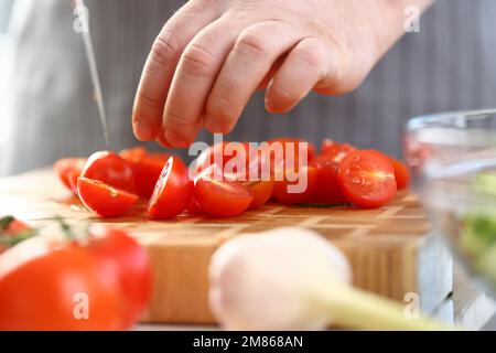 Der Küchenchef schneidet frische, reife Tomaten auf dem Schneidebrett umzingelte Zutaten Stockfoto