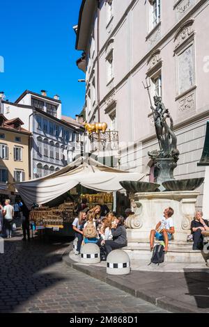 Neptunbrunnen Bozen, Blick auf die Menschen, die neben der Fontana Nettuno auf der Piazza Erbe sitzen, dem historischen Lebensmittelmarkt in Bozen Italien Stockfoto