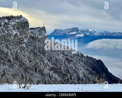 Ein Luftbild zeigt einen winterlichen französischen Wald mit einem exquisiten christlichen religiösen Emblem, das den Gipfel eines Berges ziert Stockfoto