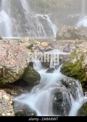 Aus nächster Nähe mit faszinierenden Szenen von Wasserfällen, die zwischen üppigen, zerklüfteten Felsformationen hindurch kaskadieren und die heitere Schönheit der Natur zeigen. Stockfoto