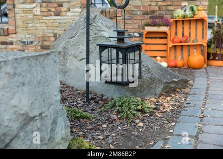 Eine schwarze Gartenlaterne hing vor einem Felshintergrund an einem Griff. Stockfoto