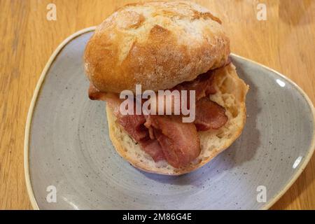 Mittagssnack in einem Yorkshire Café, gegrillter Speck in einem Sauerteigbrötchen Stockfoto