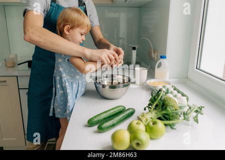 Mom bringt ihrer kleinen Tochter bei, wie man Abendessen kocht. Stockfoto