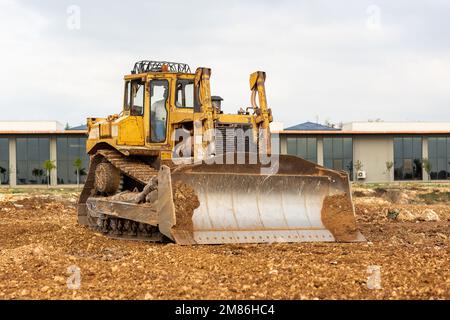 Planierraupe auf der Baustelle. Bulldozer zum Roden, Planieren, Grabenaushub und Graben von Fundamenten. Raupentraktor und Erdbewegung e Stockfoto