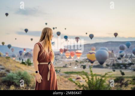Eine Touristin, die Heißluftballons in Kappadokien, Türkei, ansieht. Happy Travel in Turkey Concept. Eine Frau auf einem Berggipfel, die eine wunderbare Aussicht genießt Stockfoto