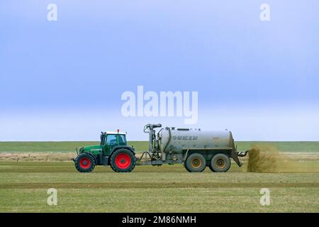 Landwirt im Fendt 818 Schlepper mit Drückstreuer verteilt/verteilt Flüssigdünger als Dünger im Frühjahr über das Feld Stockfoto