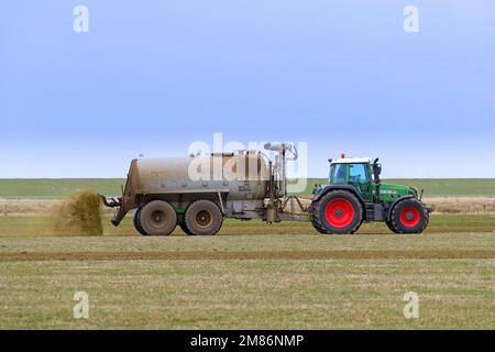 Landwirt im Fendt 818 Schlepper mit Drückstreuer verteilt/verteilt Flüssigdünger als Dünger im Frühjahr über das Feld Stockfoto