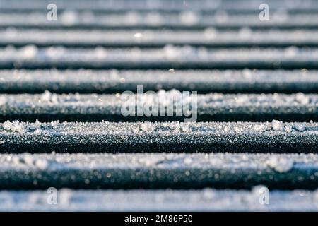 Makroaufnahme von Eiskristallen und Schnee auf Metallstreben Stockfoto