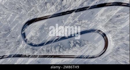 Eine gewundene Straße schlängelt sich mitten im Winter weit auf den Bergen hinauf. Stockfoto