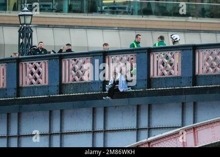 London, Großbritannien. 12. Januar 2023. Die Frau ist auf dem äußeren Rand der Brücke zu sehen, mit einer großen Präsenz von Sanitätern, Rettungsdiensten, Polizei und anderen anwesenden Personen auf der Brücke hinter der Brücke sowie auf der Themse. Die Lambeth Bridge in Westminster war für mehrere Stunden heute Nachmittag und Abend geschlossen, als eine Frau über das Geländer geklettert war, mit der Absicht, in den Fluss zu springen. Während Polizeirettungsdienste den Fluss patrouillierten, fuhren Fracht- und einige Passagierboote weiter darunter. Kredit: Imageplotter/Alamy Live News Stockfoto