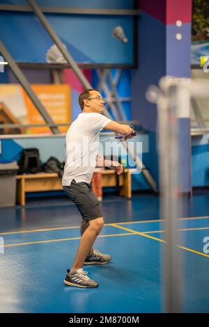 Ein Mann spielt Badminton in Sportbekleidung auf dem Hallenplatz Stockfoto