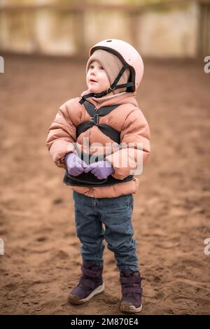 Porträt eines kleinen Mädchens in Schutzjacke und Helm vor dem Reitstunden Stockfoto