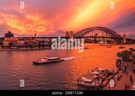 Dramatischer Sonnenuntergang über der Sydney Harbour Bridge in Australien bei Ankunft und Abfahrt der Fähren am Circular Quay Stockfoto