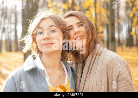 Nette, reizende Familie von Mutter und Tochter, viel Spaß zusammen, Urlaub genießen, Blätter sammeln, entspannen, in die Kamera schauen Stockfoto