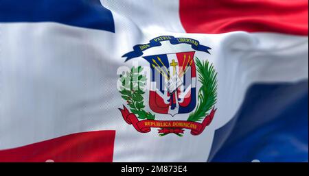 Nahaufnahme der Flagge der Dominikanischen Republik. Rote und blaue Flagge mit weißem Kreuz, Wappen in der Mitte. Geriffelter Stoff. Strukturierter Hintergrund. Selektiv für Stockfoto