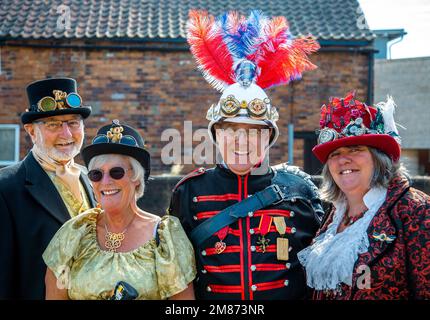 Porträt einer Gruppe von Steampunken mittleren Alters mit Periode und militärischer Steampunkkleidung. Lächelt, lacht und schaut direkt in die Kamera. Stockfoto