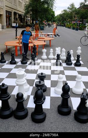 Kinder, die auf der Straße Schach spielen, mit großen Schachfiguren und Schachbrett auf der Straße von Mile enden in Le Plateau Mont Royal.Montreal.Quebec.Canada Stockfoto