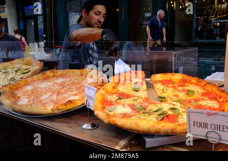 Ein männlicher Lebensmittelhändler, der während des San Gennaro Festivals in Little Italy.Manhattan.New York City.USA Pizzas zum Verkauf bereitstellt Stockfoto