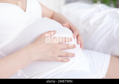 Schwangere Frauen saßen auf dem Bett, um sich auszuruhen Stockfoto