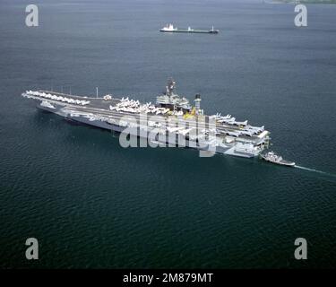 Ein Lufthafen-Viertelblick des Flugzeugträgers USS KITTY HAWK (CV-63) mit Unterstützung eines großen Hafenschleppers. Basis: Marinestützpunkt, Subic Bay Staat: Luzon Land: Philippinen (PHL) Stockfoto
